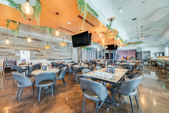 dining room featuring a towering ceiling, concrete floors, and wooden walls