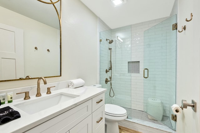 bathroom featuring hardwood / wood-style flooring, vanity, a shower with shower door, and toilet