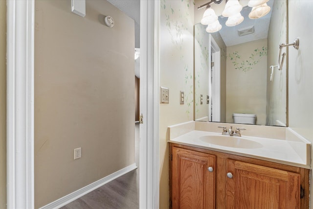 bathroom featuring a notable chandelier, a textured ceiling, toilet, vanity, and hardwood / wood-style flooring