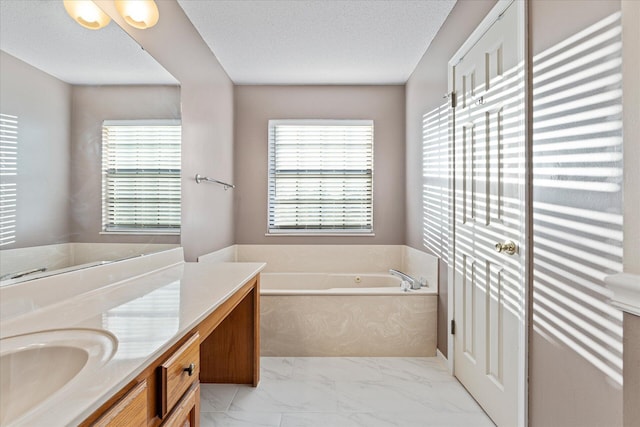 bathroom with a textured ceiling, vanity, a wealth of natural light, and a bathing tub