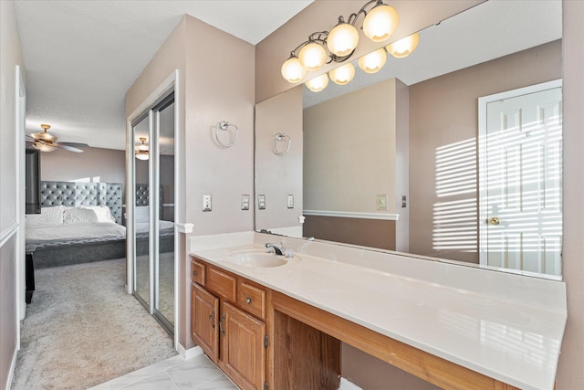 bathroom with a textured ceiling, vanity, ceiling fan, and a healthy amount of sunlight