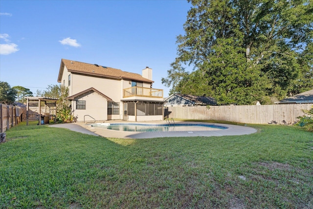 back of house with a yard, a balcony, a fenced in pool, and a sunroom