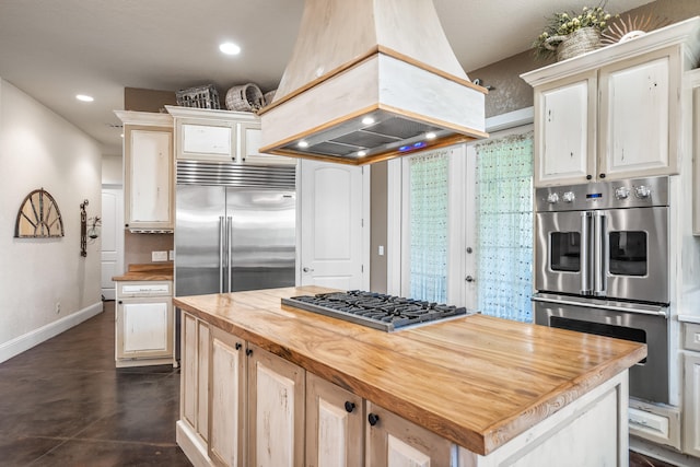 kitchen featuring premium range hood, a center island, stainless steel appliances, and wood counters