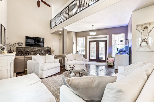 living room with french doors, ceiling fan, dark wood-type flooring, and a high ceiling