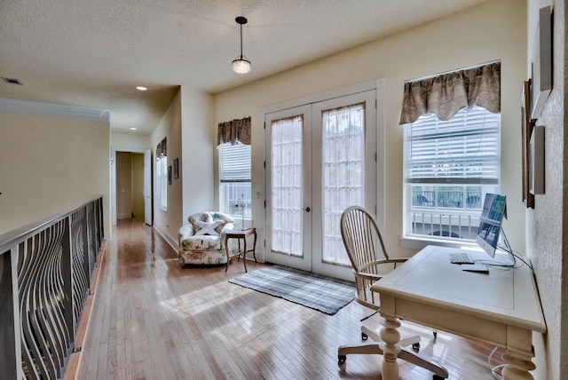 office area with french doors, light hardwood / wood-style floors, and a textured ceiling