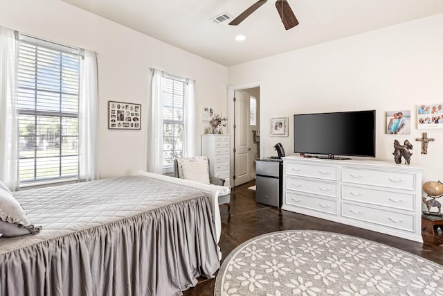 bedroom featuring ceiling fan, dark hardwood / wood-style flooring, and multiple windows