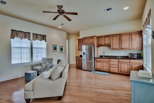 kitchen featuring ceiling fan, sink, light hardwood / wood-style flooring, stainless steel fridge, and a textured ceiling