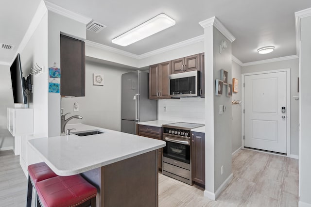 kitchen featuring crown molding, sink, appliances with stainless steel finishes, dark brown cabinets, and light hardwood / wood-style floors