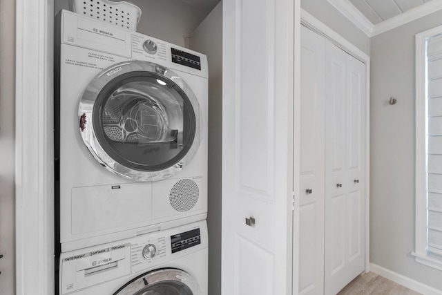 washroom featuring light wood-type flooring, stacked washer / drying machine, and ornamental molding