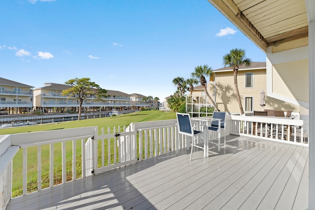 wooden terrace featuring a water view and a yard