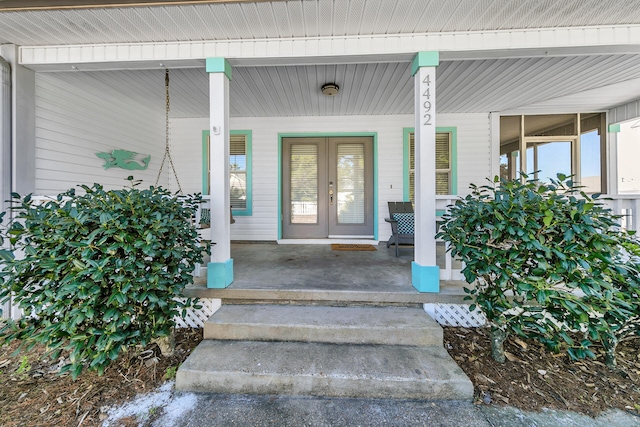 view of exterior entry featuring french doors and a porch