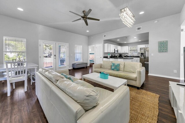 living room featuring ceiling fan with notable chandelier and dark hardwood / wood-style floors