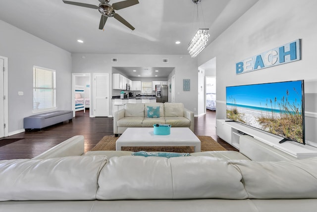 living room with ceiling fan with notable chandelier and dark wood-type flooring