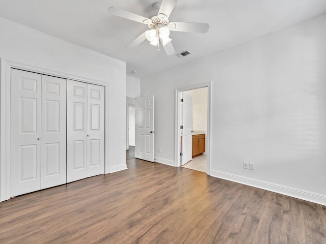 unfurnished bedroom featuring connected bathroom, a closet, light hardwood / wood-style flooring, and ceiling fan