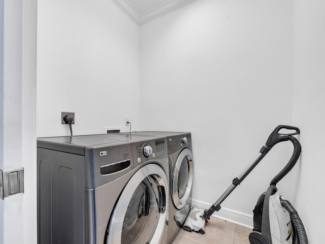 clothes washing area featuring light tile patterned flooring, ornamental molding, and washing machine and clothes dryer