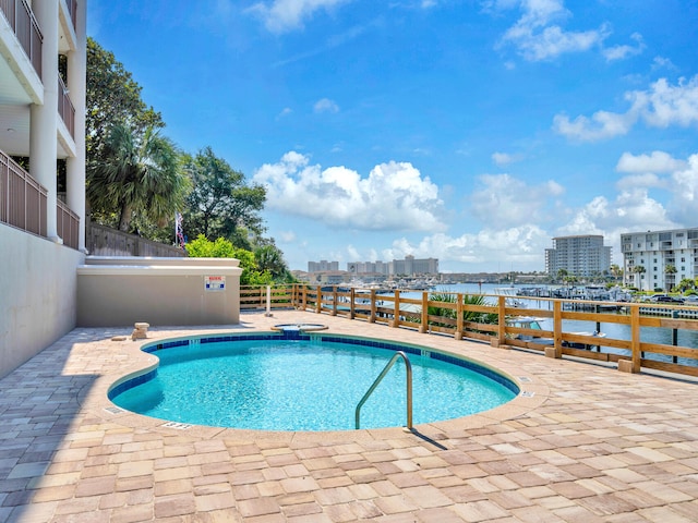 view of pool featuring a water view and a patio