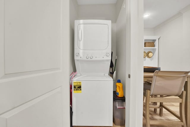 laundry area with hardwood / wood-style floors and stacked washer and dryer