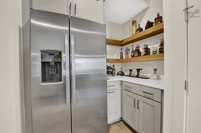 kitchen with stainless steel fridge, light hardwood / wood-style floors, and white cabinetry