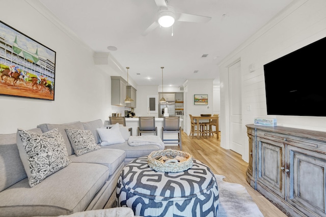 living room featuring ceiling fan, light hardwood / wood-style floors, and ornamental molding