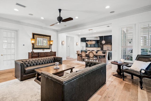 living room featuring ceiling fan, crown molding, and light wood-type flooring