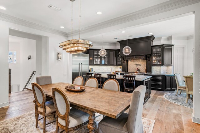 dining room with crown molding, light hardwood / wood-style flooring, and a chandelier