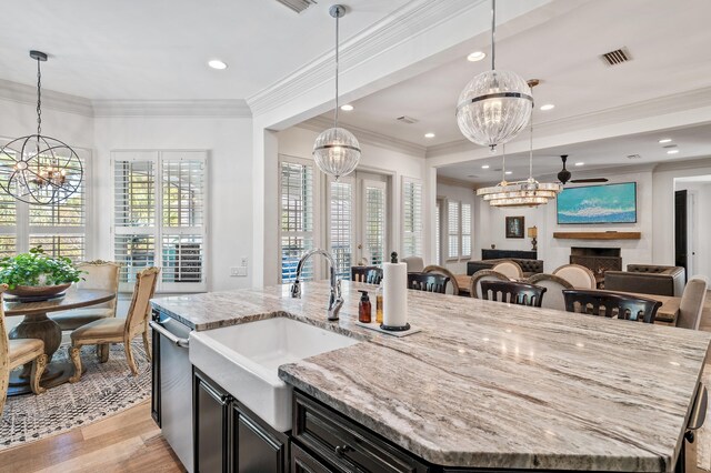 kitchen with pendant lighting, light hardwood / wood-style flooring, a spacious island, and sink