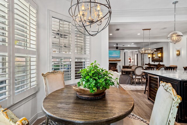 dining space with light hardwood / wood-style floors, wine cooler, and ornamental molding