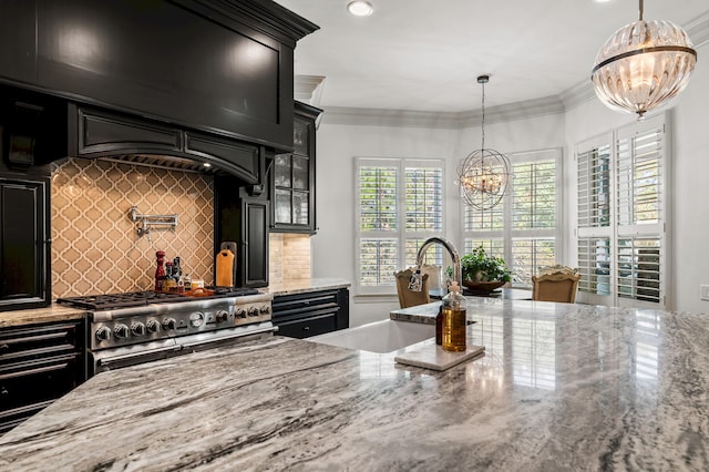 kitchen with a chandelier, decorative light fixtures, light stone counters, and sink