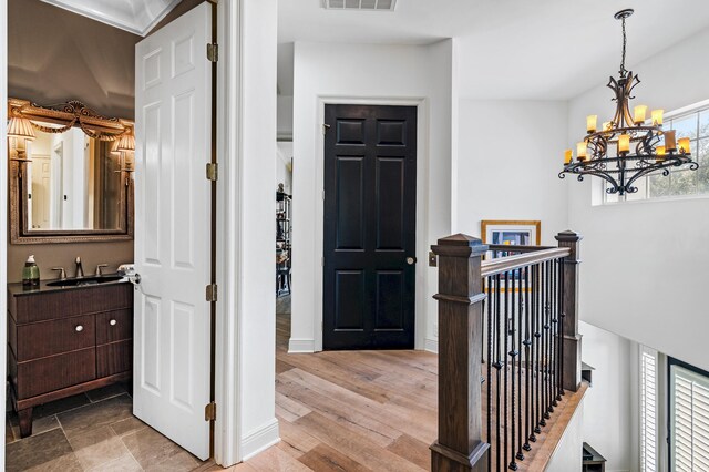 entrance foyer with light wood-type flooring, a wealth of natural light, a notable chandelier, and sink