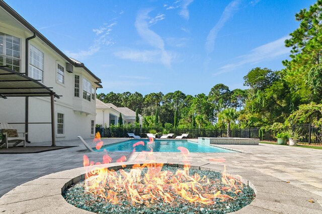 view of swimming pool featuring pool water feature, a patio area, and an outdoor fire pit