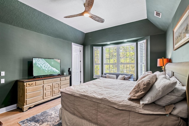 bedroom featuring light hardwood / wood-style floors, vaulted ceiling, and ceiling fan