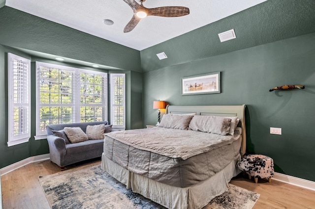 bedroom with ceiling fan, a textured ceiling, and light hardwood / wood-style flooring