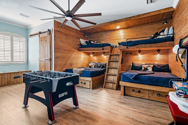 recreation room with ceiling fan, wooden walls, light hardwood / wood-style floors, and ornamental molding