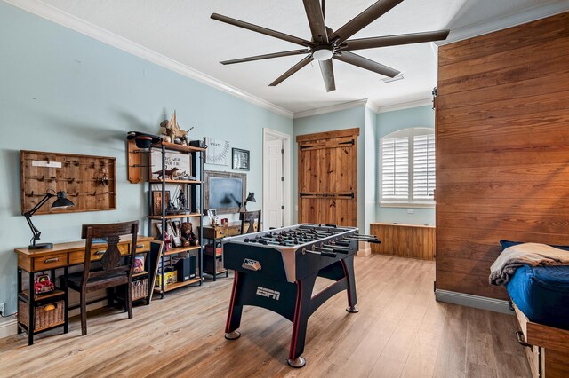 recreation room with wooden walls, light hardwood / wood-style flooring, ceiling fan, and ornamental molding