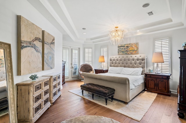 bedroom featuring hardwood / wood-style floors, access to exterior, french doors, and a tray ceiling