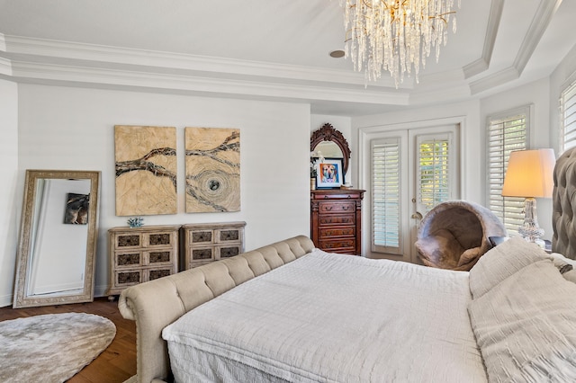 bedroom featuring hardwood / wood-style floors, crown molding, access to exterior, a tray ceiling, and a chandelier