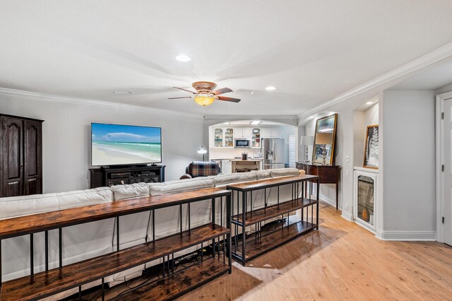 living room with ceiling fan, light wood-type flooring, and ornamental molding