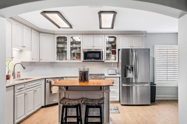 kitchen with a kitchen breakfast bar, white cabinetry, light hardwood / wood-style flooring, and stainless steel appliances