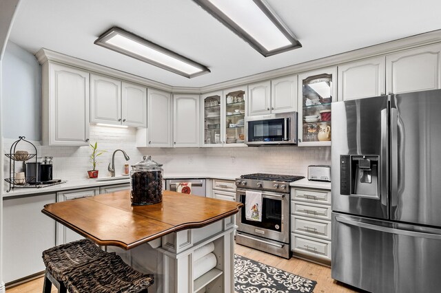 kitchen featuring appliances with stainless steel finishes, backsplash, sink, white cabinets, and light hardwood / wood-style floors