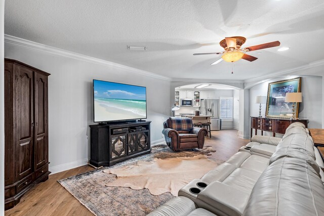 living room featuring a textured ceiling, light hardwood / wood-style flooring, ceiling fan, and ornamental molding