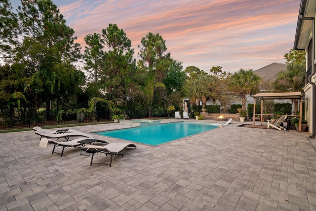 pool at dusk with an outdoor fire pit and a patio area