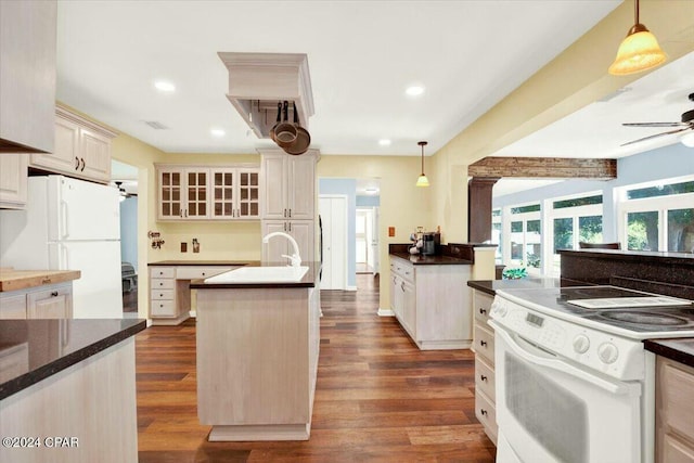 kitchen with white appliances, a kitchen island with sink, dark wood-type flooring, ceiling fan, and pendant lighting