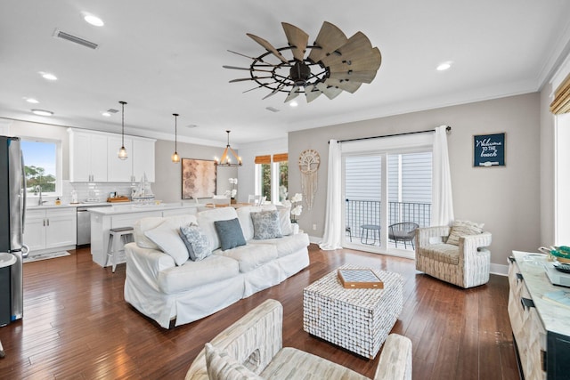 living room featuring sink, dark wood-type flooring, ceiling fan with notable chandelier, and ornamental molding