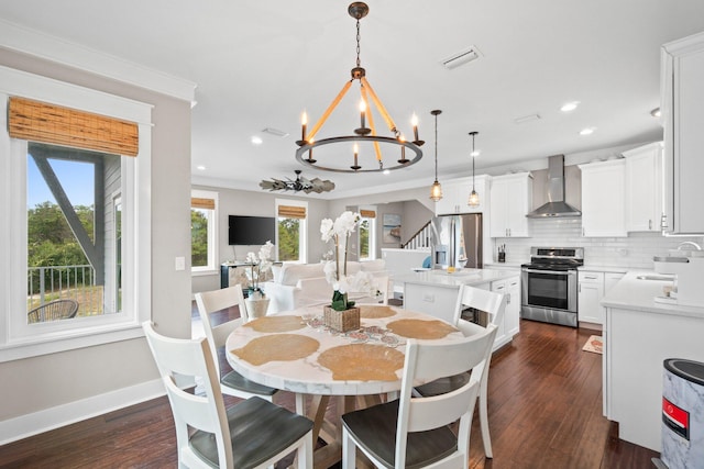 dining space with dark hardwood / wood-style floors, sink, crown molding, and a chandelier