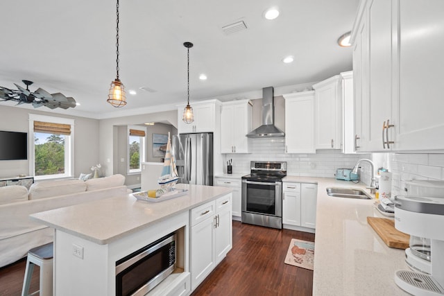 kitchen with white cabinets, appliances with stainless steel finishes, wall chimney exhaust hood, and sink