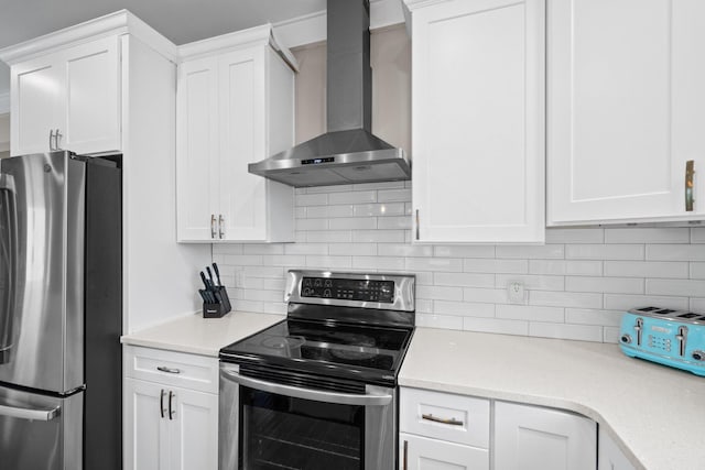 kitchen with tasteful backsplash, white cabinets, wall chimney range hood, and appliances with stainless steel finishes