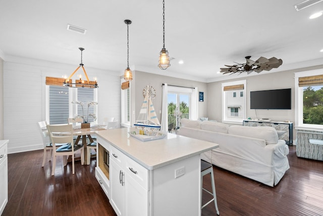 kitchen with white cabinetry, a center island, dark hardwood / wood-style flooring, decorative light fixtures, and ceiling fan with notable chandelier