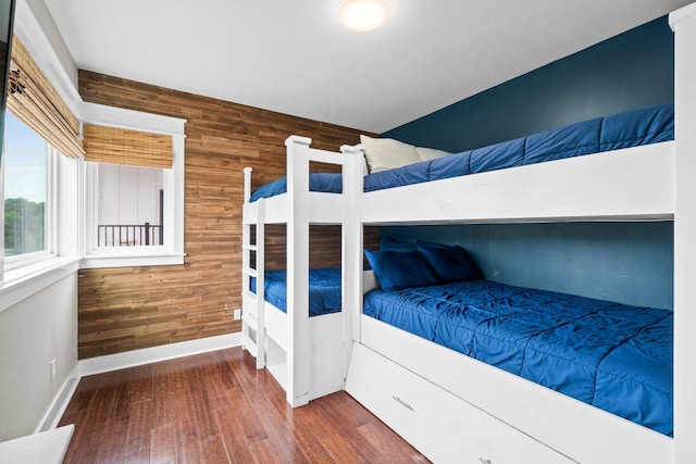 bedroom with dark hardwood / wood-style floors and wood walls