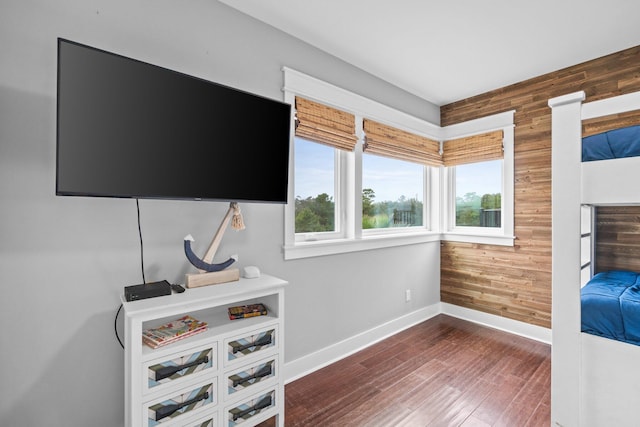 bedroom with dark wood-type flooring and wood walls