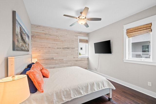 bedroom with wooden walls, ceiling fan, and dark hardwood / wood-style floors